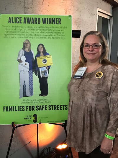 Kristi Finney Dunn stands next to a posterboard proclaiming her the winner of the Alice Award for transportation advocacy.