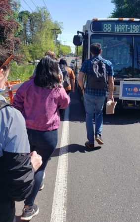 People walking single file to board bus in dangerous roadway