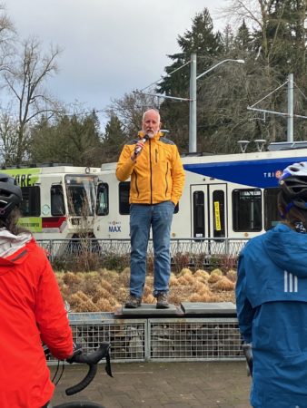 Outgoing Milwaukie Mayor Mark Gamba addresses the crowd of 80 in front of a MAX train in Milwaukie.
