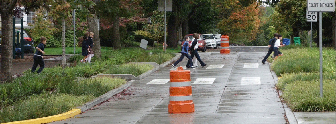 Several children walking and running across a street in a crosswalk