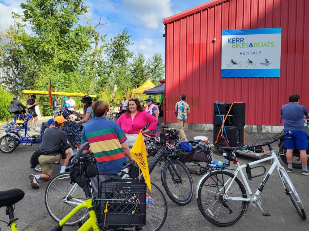People standing by their bikes socializing outside of Kerr Bikes and Boats rentals.