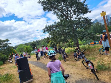 Gravel trail by the Willamette River where the group of riders parked there bikes and are standing around socializing.