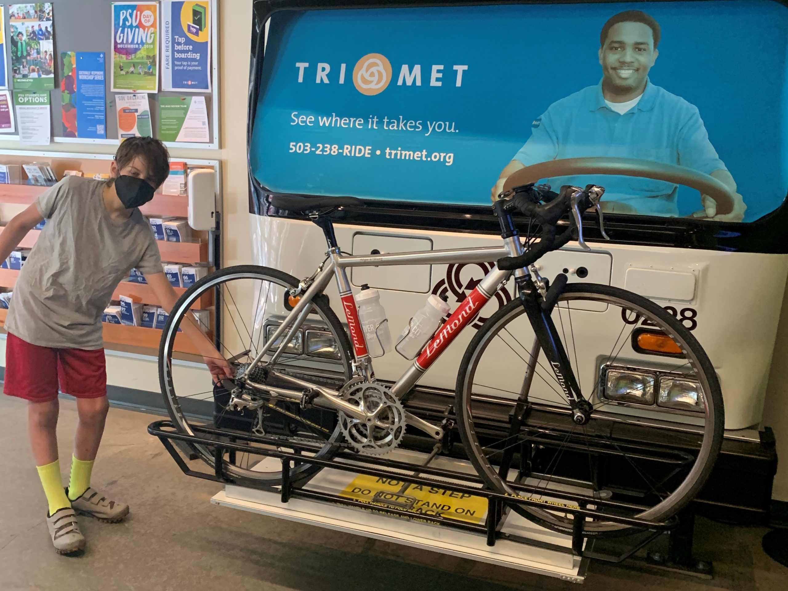 A teenager poses next to his bike on a bus rack