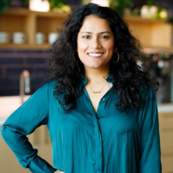 Dark haried woman, in greean shirt, hand on hip, smiling